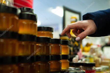 Puesto de miel en una feria con frascos de miel y material de la marca